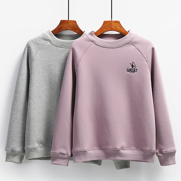 Ένα καθαρό μοντέλο γυναικείου φούτερ με κεντημένη επιγραφή και οβάλ λαιμόκοψη