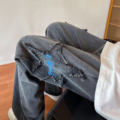 Széles szabású férfi farmernadrág szakadt motívumokkal és feliratokkal