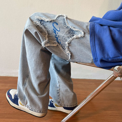 Széles szabású férfi farmernadrág szakadt motívumokkal és feliratokkal