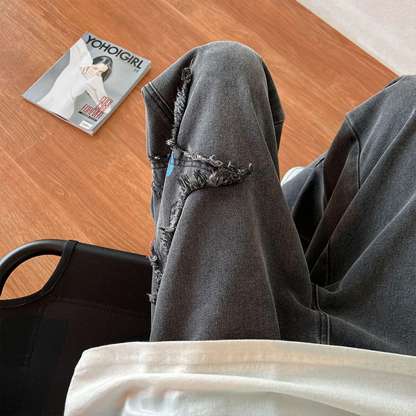 Széles szabású férfi farmernadrág szakadt motívumokkal és feliratokkal