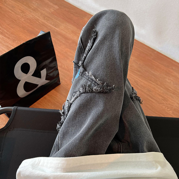 Széles szabású férfi farmernadrág szakadt motívumokkal és feliratokkal