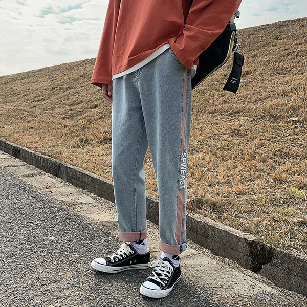 Värvilise kaunistuse ja kirjaga meeste teksad