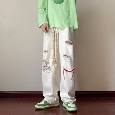 Szakadt motívumokkal és hímzéssel ellátott férfi farmer