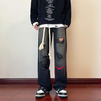 Szakadt motívumokkal és hímzéssel ellátott férfi farmer