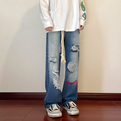 Szakadt motívumokkal és hímzéssel ellátott férfi farmer