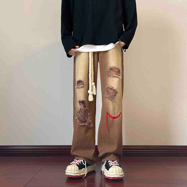 Szakadt motívumokkal és hímzéssel ellátott férfi farmer