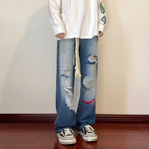 Szakadt motívumokkal és hímzéssel ellátott férfi farmer