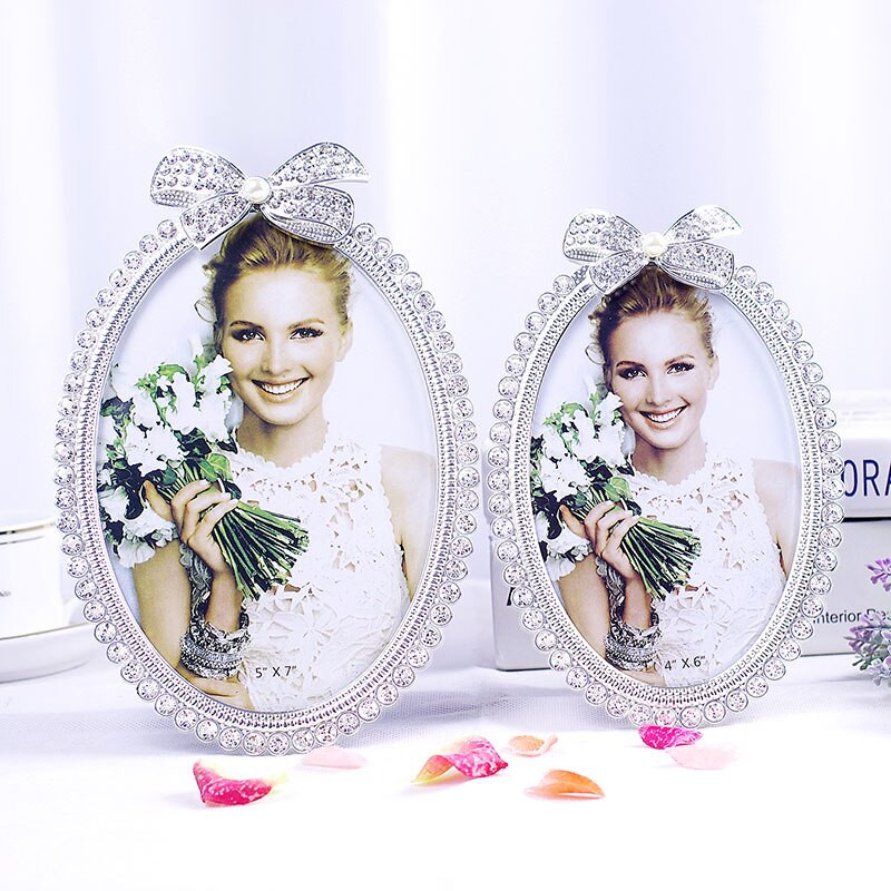 Blizgus sidabru padengtas cinko lydinio paveikslų rėmelis su baltais perlais ir skaidriais kalnų krištolais papuošta 3 dydžių apvalių ovalių formų juostele