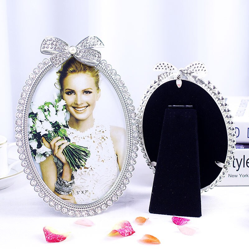 Blizgus sidabru padengtas cinko lydinio paveikslų rėmelis su baltais perlais ir skaidriais kalnų krištolais papuošta 3 dydžių apvalių ovalių formų juostele